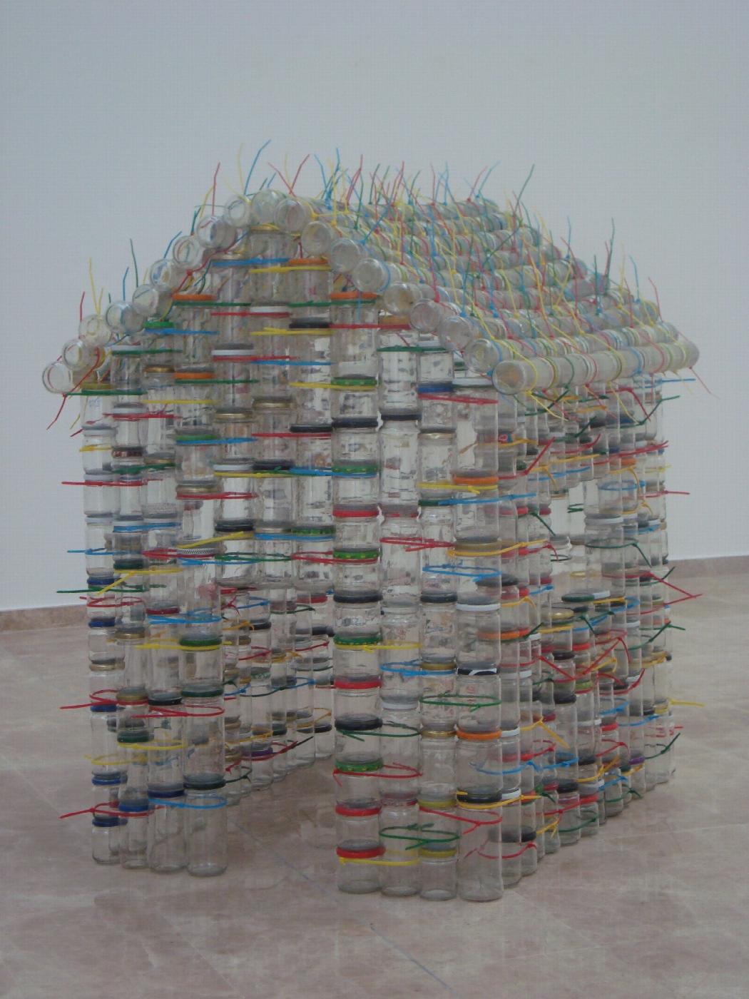Escultura de Carmen Marcos (2009-2012) realizada con botes de vidrio reciclados que habla de las acrobacias familiares para llegar a fin de mes y pone en valor el reciclaje